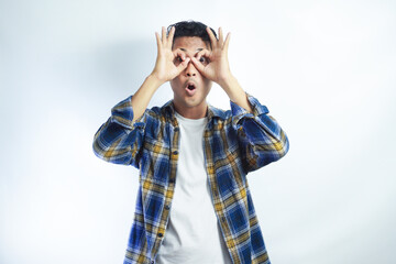 Young creative man holding fingers near eyes like glasses