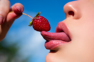 Strawberry in lips. Summer sexy fruits. Red strawberry in woman mouths close up.