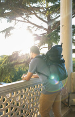 Male tourist with backpack, sunbeam. View from the back, tourist destinations. Standing, vacation in summer, autumn, spring.