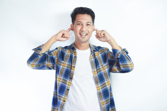 Adult Asian man smiling while covering his ears with finger