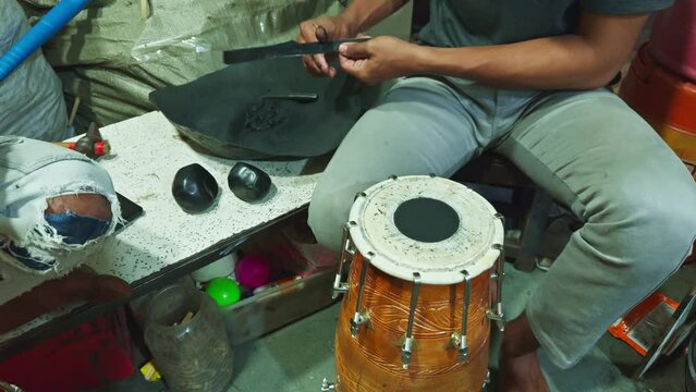 Artisan crafting traditional musical instruments focused on attaching skins to tambourine frames in a workshop man repairing drum at musical workshop