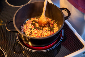Kleingeschnittene Zwiebeln anbraten und in einem Topf mit einem Holzlöffel umrühren