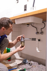 Plumber's hand holds joints and joints of sink or sink in bathroom, Cleaning clogged sink in...