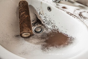 Falling dirty particles from a water filter in a white washbasin. Elements of a filtration system...