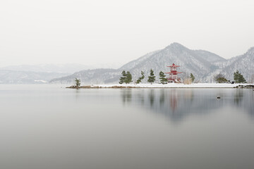 Ukimido temple at lake toya Hokkaido against winter mountains backdrop
