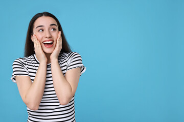 Portrait of happy surprised woman on light blue background. Space for text
