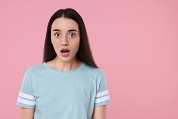 Fototapeta premium Portrait of surprised woman on pink background. Space for text