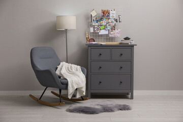 Stylish room interior with vision board, rocking chair and chest of drawers
