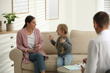 Child psychotherapist working with little girl and her mother in office - obrazy, fototapety, plakaty