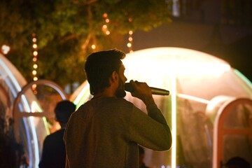 Male Singer Singing In A Party With Beautiful Lights As Background