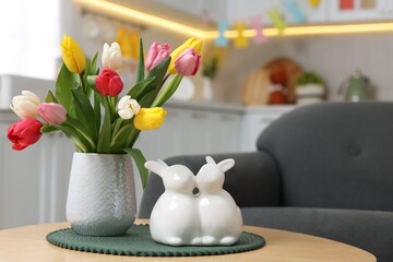 Easter decorations. Bouquet of tulips and bunny figures on table indoors, closeup. Space for text