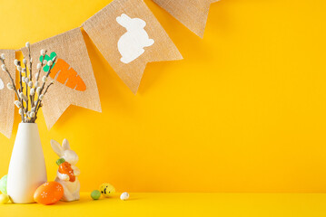 Celebrate Easter mood. A side view of a table adorned with figurine bunny with carrot, multicolored eggs, pussy willow in a vase, and a farmhouse garland on an orange backdrop with space for wording