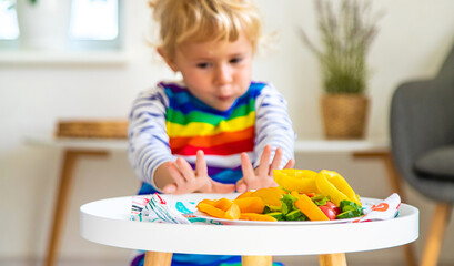 Child eats vegetables at home. Selective focus.