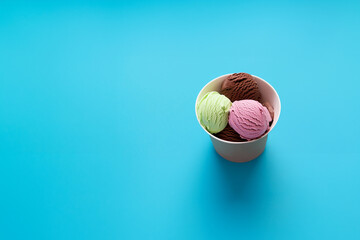 Colorful ice cream scoops in a paper cup on blue background