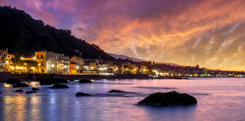 evening or night landscape of evening town coastline in golden lights and sea gulf with calm water...