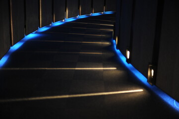 Blue lights in a long, curved, dark corridor or tunnel of a hall. Geometrical pattern and...
