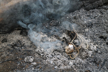 Burning plastic and paper waste on the ground. Smoke and ash from burning rubbish