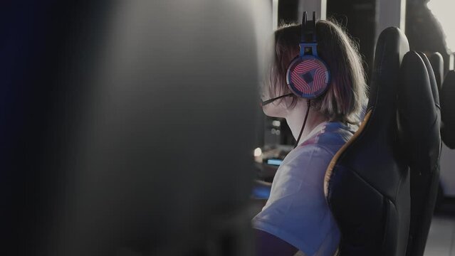 Serious focused teen gamer in headset playing PC video game at computer club during cyber sport tournament. E-sport championship. Modern multiplayer online real-time strategy RTS, tactics skill