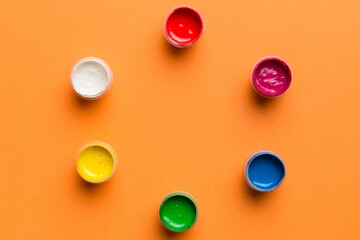 jars with gouache of different colors on Colored background. hobby painting. Top view with empty space. workplace for creativity. home teaching concept drawing