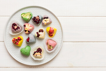 Plate with different chocolate on colored background. Assortment of fine chocolates top view vith copy space Health and obesity concept