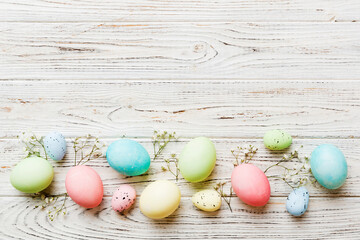 Happy Easter composition. Easter eggs on colored table with gypsophila. Natural dyed colorful eggs background top view with copy space