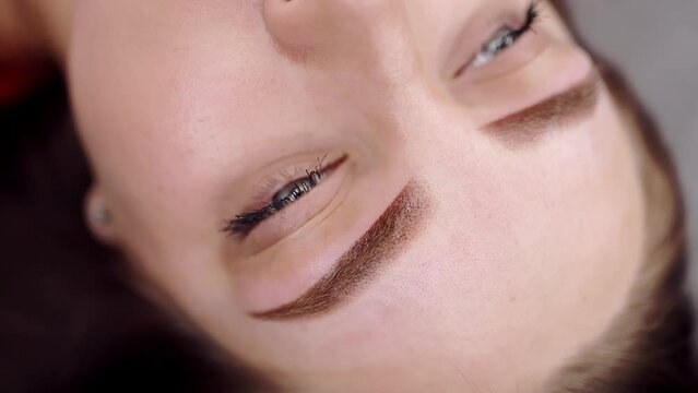 A young girl who had a permanent eyebrow makeup procedure performed, the girl looks into the camera. Permanent makeup procedure, performing PMU of eyebrows