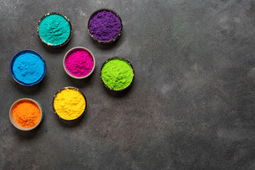 Obraz na płótnie Canvas Organic colors Gulal in bowl for Holi festival on dark background. Colorful Holi powders. Top view, flat lay, copy space.