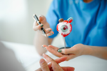 A female doctor conducts a medicine appointment in a clinic room at the desk, focusing on eye...