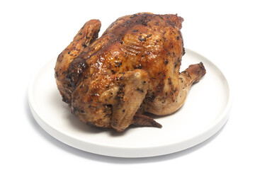 A whole delicious roasted chicken seasoned with herbs in a white plate isolated on white background clipping path