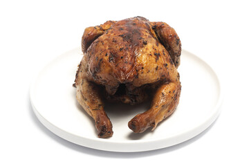 A whole delicious roasted chicken seasoned with herbs in a white plate isolated on white background clipping path