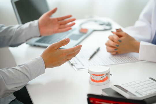 Engaging dental consultation with a female model discussing men's dental appointments at a professional desk meeting, emphasizing oral health and dental care for men.