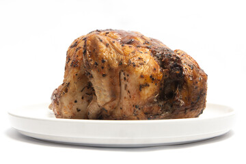 A whole delicious roasted chicken seasoned with herbs in a white plate isolated on white background clipping path