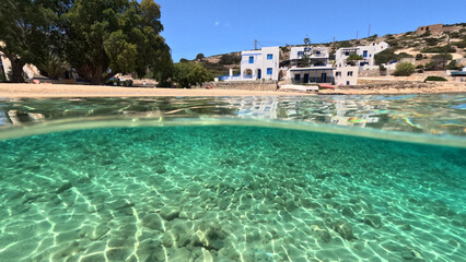 Underwater split photo of paradise crystal clear sea beach of Agios Georgios in main port of Irakleia island covered in Armirikia trees providing natural shade, small Cyclades, Greece