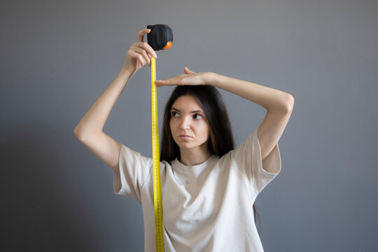 Young girl Checking Her Height With a Yellow Measuring Tape Indoors