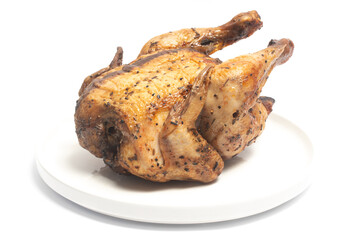 A whole delicious roasted chicken seasoned with herbs in a white plate isolated on white background clipping path