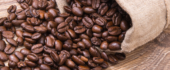Heap of dark roasted coffee grains in jute bag