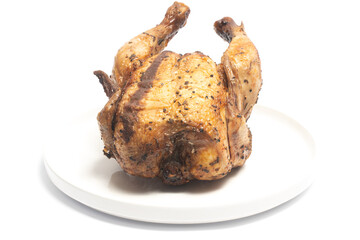 A whole delicious roasted chicken seasoned with herbs in a white plate isolated on white background clipping path