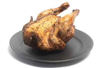 A whole delicious roasted chicken seasoned with herbs in a black plate isolated on white background clipping path
