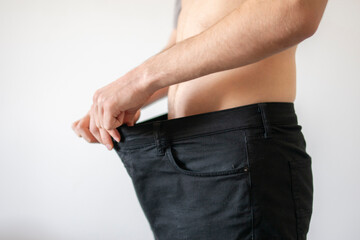 Man Showcasing Significant Weight Loss by Holding Oversized Jeans