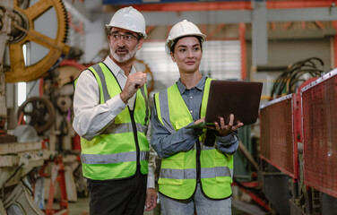 Senior manager train female apprentice technician in metalwork production factory. Industrial engineer team standing working in manufacturing facility talking machinery maintenance in heavy steel job