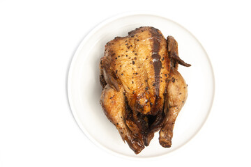 A whole delicious roasted chicken seasoned with herbs in a white plate top view isolated on white background clipping path