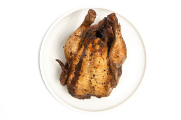 A whole delicious roasted chicken seasoned with herbs in a white plate top view isolated on white background clipping path