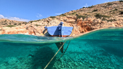 Underwater split photo of traditional fishing boat anchored in small secluded fjord and paradise...