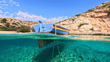 Underwater split photo of traditional fishing boat anchored in crystal clear sea of Mykonos island,...