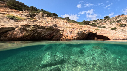 Underwater split photo of paradise fjord rocky bay of Tourkopigado, Iraklia island, small Cyclades, Greece