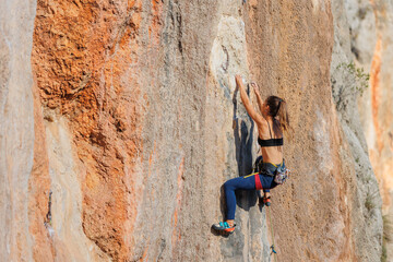 rock climber girl. rock climber girl climbs an overhanging rock.