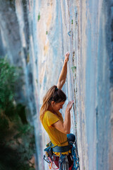 A woman climbs a rock, a strong girl trains strength and endurance, extreme sport, rock climbing..
