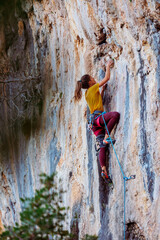 The girl climbs the rock. The climber trains on natural terrain. Extreme sport.  A woman overcomes a difficult route rock climbing..