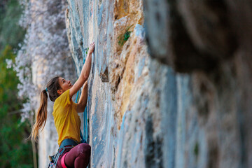 Climber overcomes challenging climbing route. A girl climbs a rock. Woman engaged in extreme sport. .