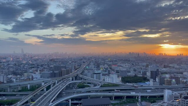 HIGASHI OSAKA, JAPAN - JULY 2023 : Aerial view of high way, road junction and cityscape of downtown district in sunset. Japanese transportation, street traffic and urban city concept video.
